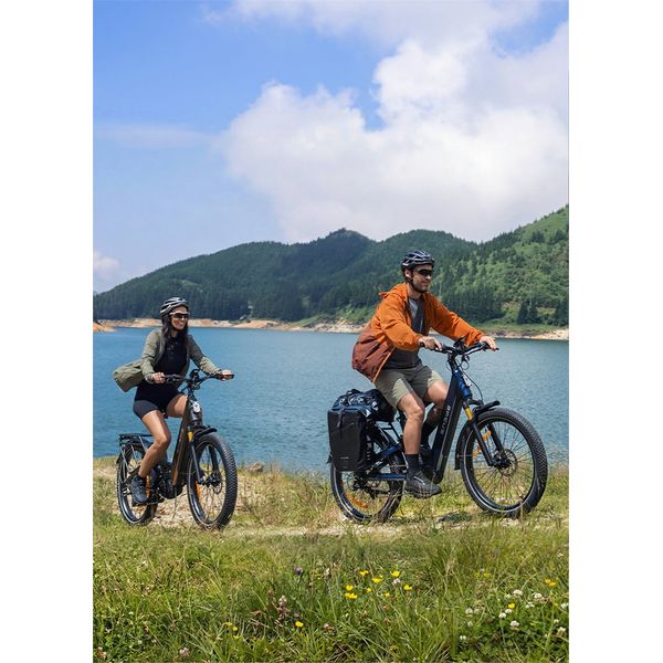 Doi bicicliști merg pe biciclete electrice pe un drum de lângă lac
