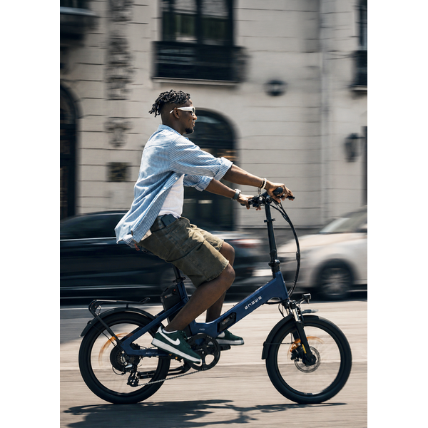 Ciclist deplasându-se prin oraș pe o bicicletă electrică pliabilă ENGWE de culoare albastru închis