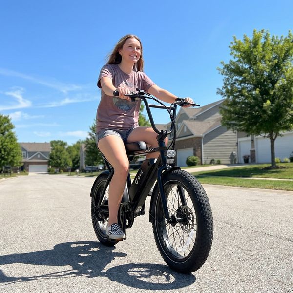 Biciclistă pe bicicleta electrică neagră DYU UX BMX, pe o stradă dintr-un cartier rezidențial